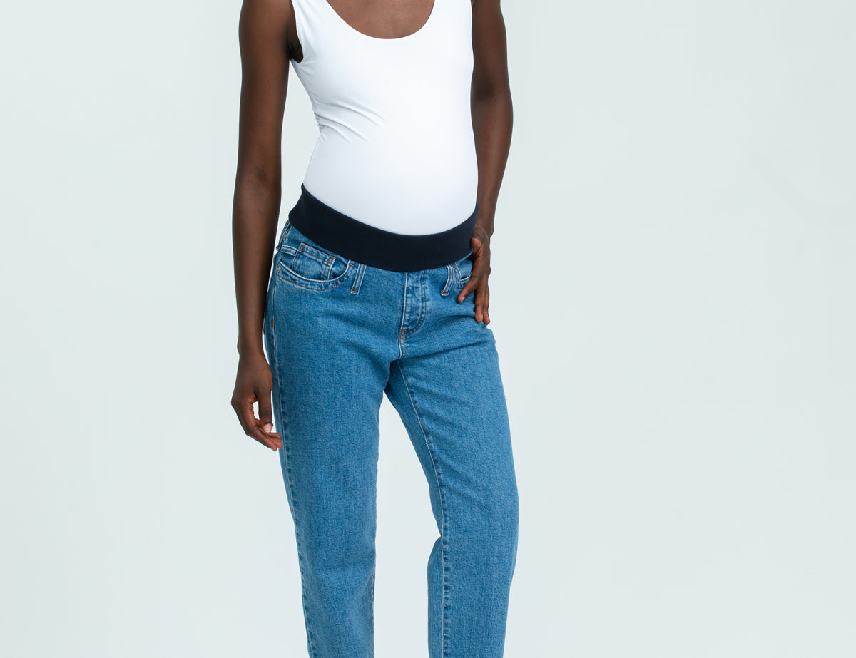 Woman wearing blue maternity jeans and white vest top