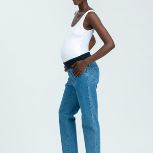 Woman wearing blue maternity jeans and white vest top