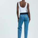 Woman wearing blue maternity jeans and white vest top