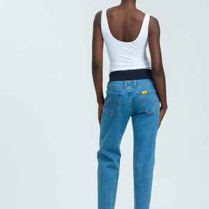 Woman wearing blue maternity jeans and white vest top