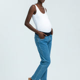 Woman wearing blue maternity jeans and white vest top