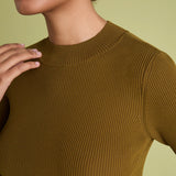Close-up of a model wearing a ribbed short-sleeve crewneck top in a warm olive-brown color, set against a solid pale yellow-green background.