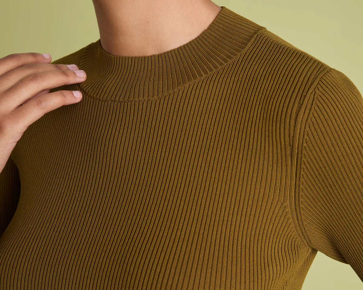 Close-up of a model wearing a ribbed short-sleeve crewneck top in a warm olive-brown color, set against a solid pale yellow-green background.