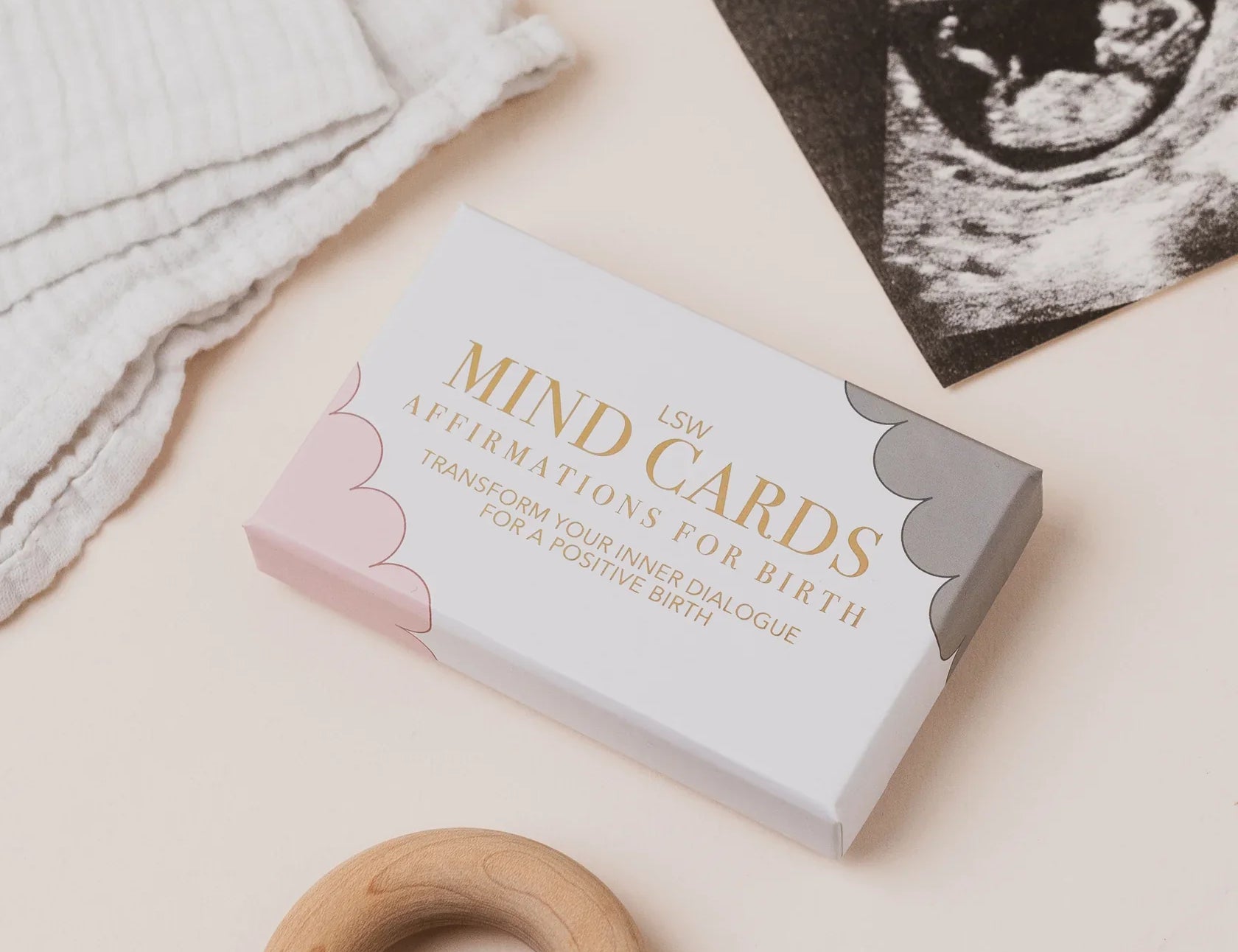 Box of 'Mind Cards' affirmations for birth on a light background with a wooden ring and ultrasound photo.