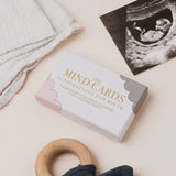 Box of 'Mind Cards' affirmations for birth on a light background with a wooden ring and ultrasound photo.