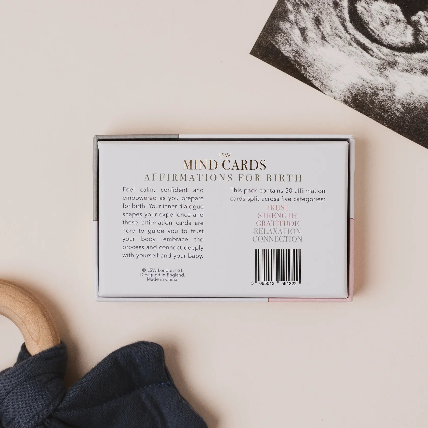 Box of 'MIND CARDS Affirmations for Birth' on a neutral background with a baby item and ultrasound photo.