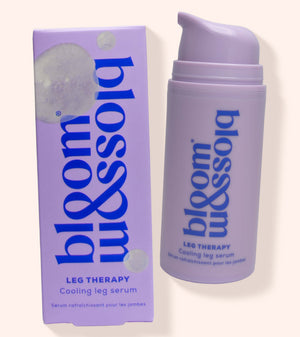A lavender pump bottle and matching box of bloom blossom leg therapy cooling leg serum on a light beige background.