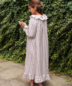 Beatrice Rose Stripe nightie back view on a woman by an ivy wall, showing the ruffled collar and tiered hem