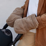 Astrid Eco stroller mittens in Mocha Borg worn by an adult with both hands on a black pram handlebar