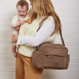 Freya Eco Stroller Organiser in Mocha Borg worn crossbody by a woman while she holds a smiling baby