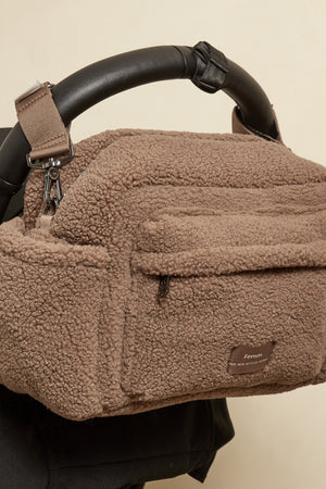Freya Eco Stroller Organiser in Mocha Borg hanging from the black handlebar of a pushchair, front pocket facing out