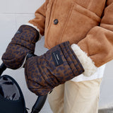Woman wearing the Astrid stroller mittens in Chocolate Leopard on a stroller handle, with cream fleece cuffs