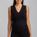 Woman wearing a black sleeveless top and leggings on a gray background