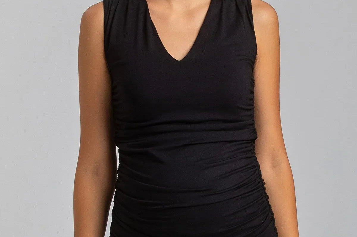 Woman wearing a black sleeveless top and leggings on a gray background
