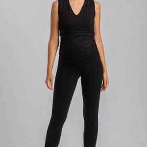 Woman wearing a black sleeveless top and leggings on a gray background