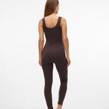 A woman viewed from behind wearing a dark brown sleeveless bodysuit and matching leggings against a plain white studio background.
