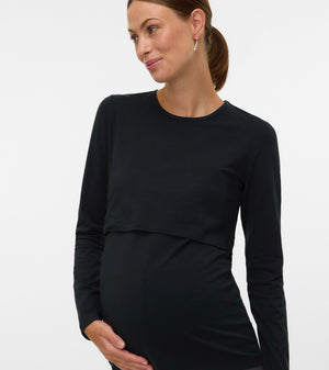 A pregnant woman wearing a black long-sleeve maternity top with a layered underbust design, shown against a plain light gray studio background.