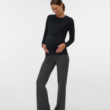 Woman wearing a black long-sleeve top and gray pants on a white background