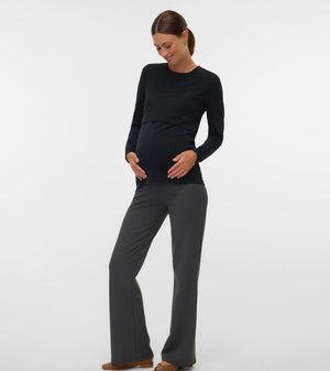 Woman wearing a black long-sleeve top and gray pants on a white background