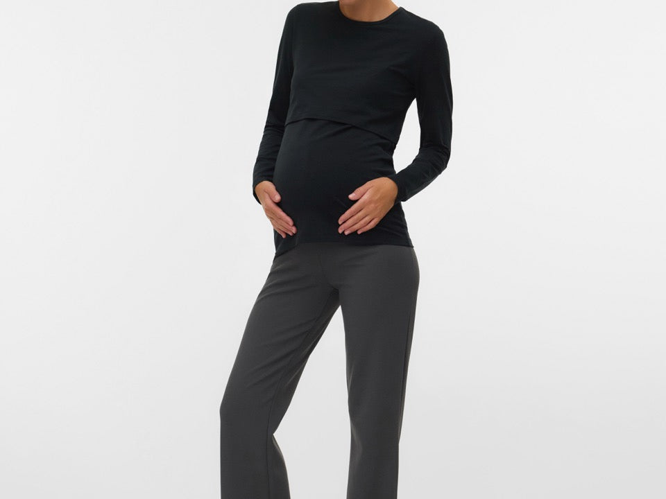 Woman wearing a black long-sleeve top and gray pants on a white background