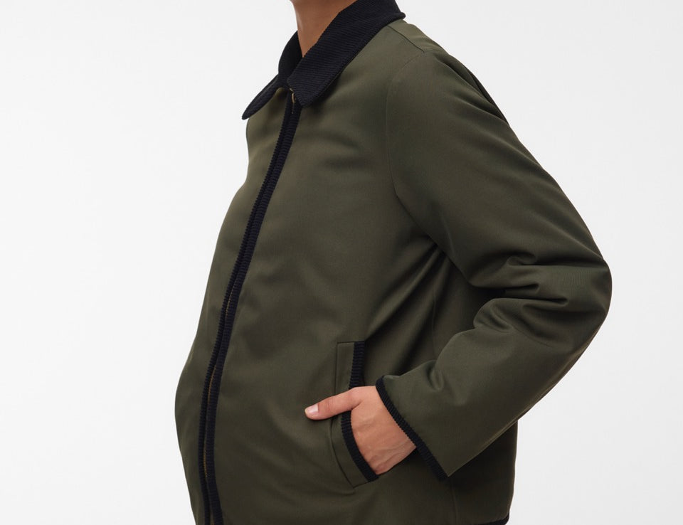 Pregnant woman wearing Khaki green short jacket with black collar and zip front