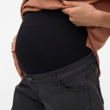 Person wearing a black maternity shirt and gray pants on a white background