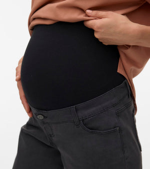 Person wearing a black maternity shirt and gray pants on a white background