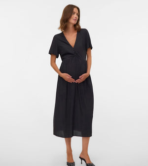 Woman wearing a black dress standing against a white background