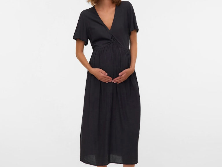 Woman wearing a black dress standing against a white background