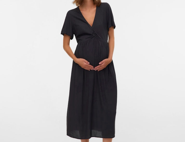 Woman wearing a black dress standing against a white background
