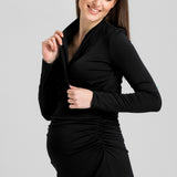 Black Helena nursing dress on a smiling pregnant woman lifting the wrap front panel to show the nursing opening