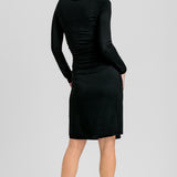 Black Helena nursing dress, back view on a woman glancing over her shoulder, showing the plain back and knee-length skirt