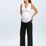 Woman wearing a white sleeveless top and black pants on a white background