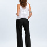 Woman wearing a white tank top and black pants on a white background