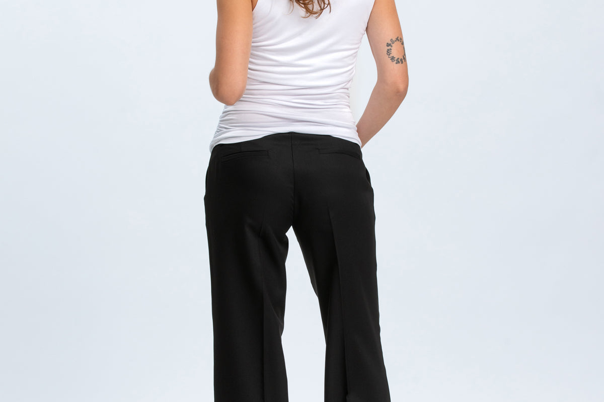 Woman wearing a white tank top and black pants on a white background