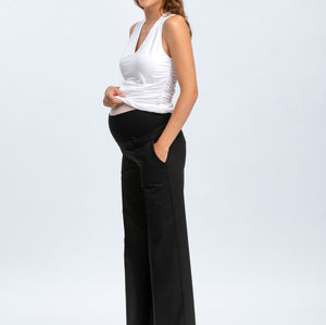 Woman wearing a white sleeveless top and black high-waisted pants on a white background