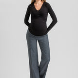 A pregnant woman modeling a black long-sleeve V-neck maternity top and heather gray wide-leg pants against a light gray studio background.