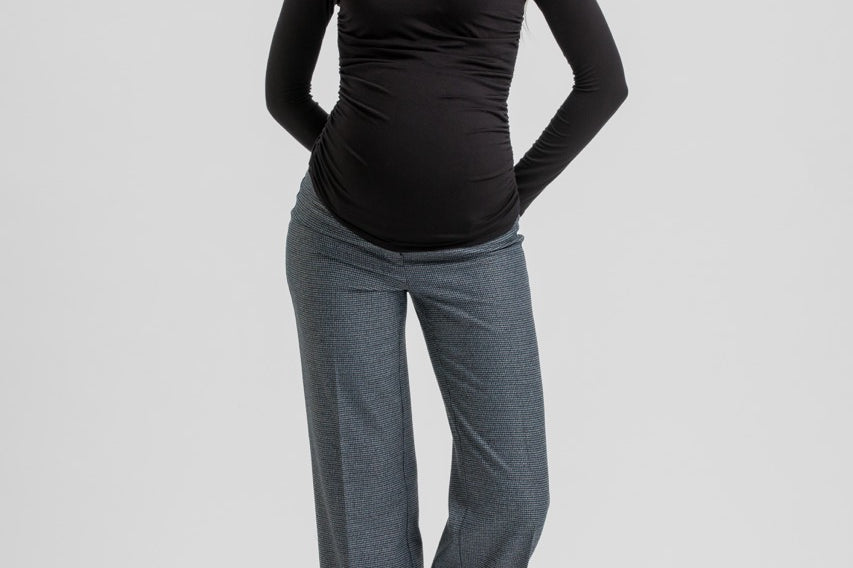 A pregnant woman modeling a black long-sleeve V-neck maternity top and heather gray wide-leg pants against a light gray studio background.