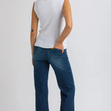 Woman wearing white top and dark blue wide leg maternity jeans on white background