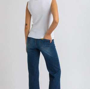 Woman wearing white top and dark blue wide leg maternity jeans on white background