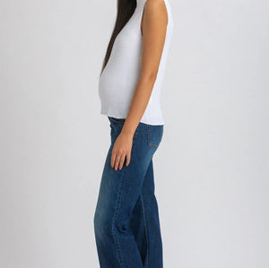 Woman wearing white top and dark blue wide leg maternity jeans on white background