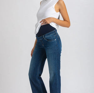 Woman wearing a white top and blue jeans on a plain background