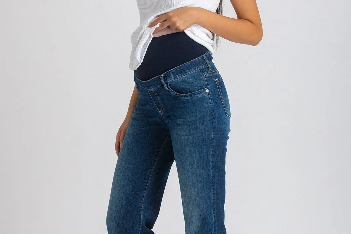 Woman wearing a white top and blue jeans on a plain background