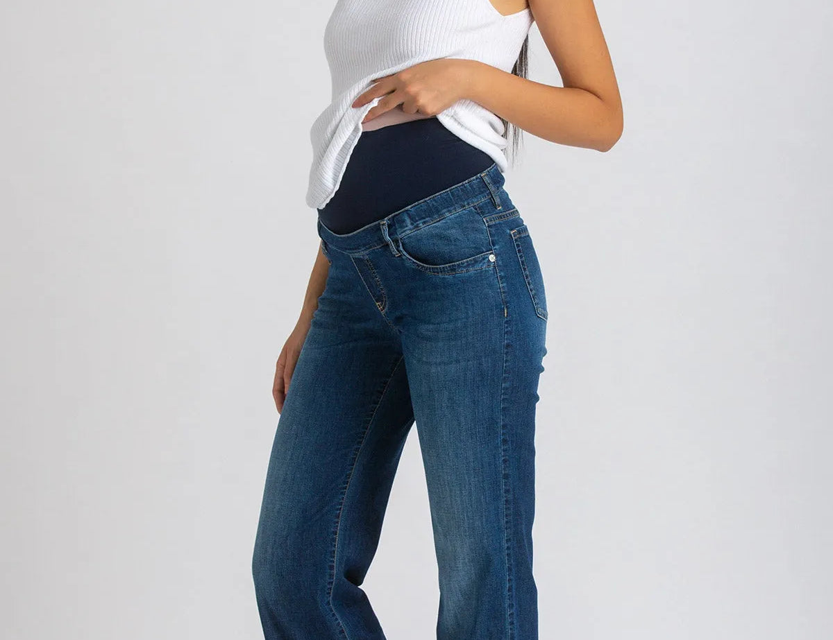 Woman wearing a white top and blue jeans on a plain background