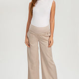 Woman wearing a white sleeveless top and beige wide-leg pants on a white background