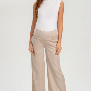 Woman wearing a white sleeveless top and beige wide-leg pants on a white background