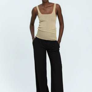 Woman wearing black linen trousers and beige vest top