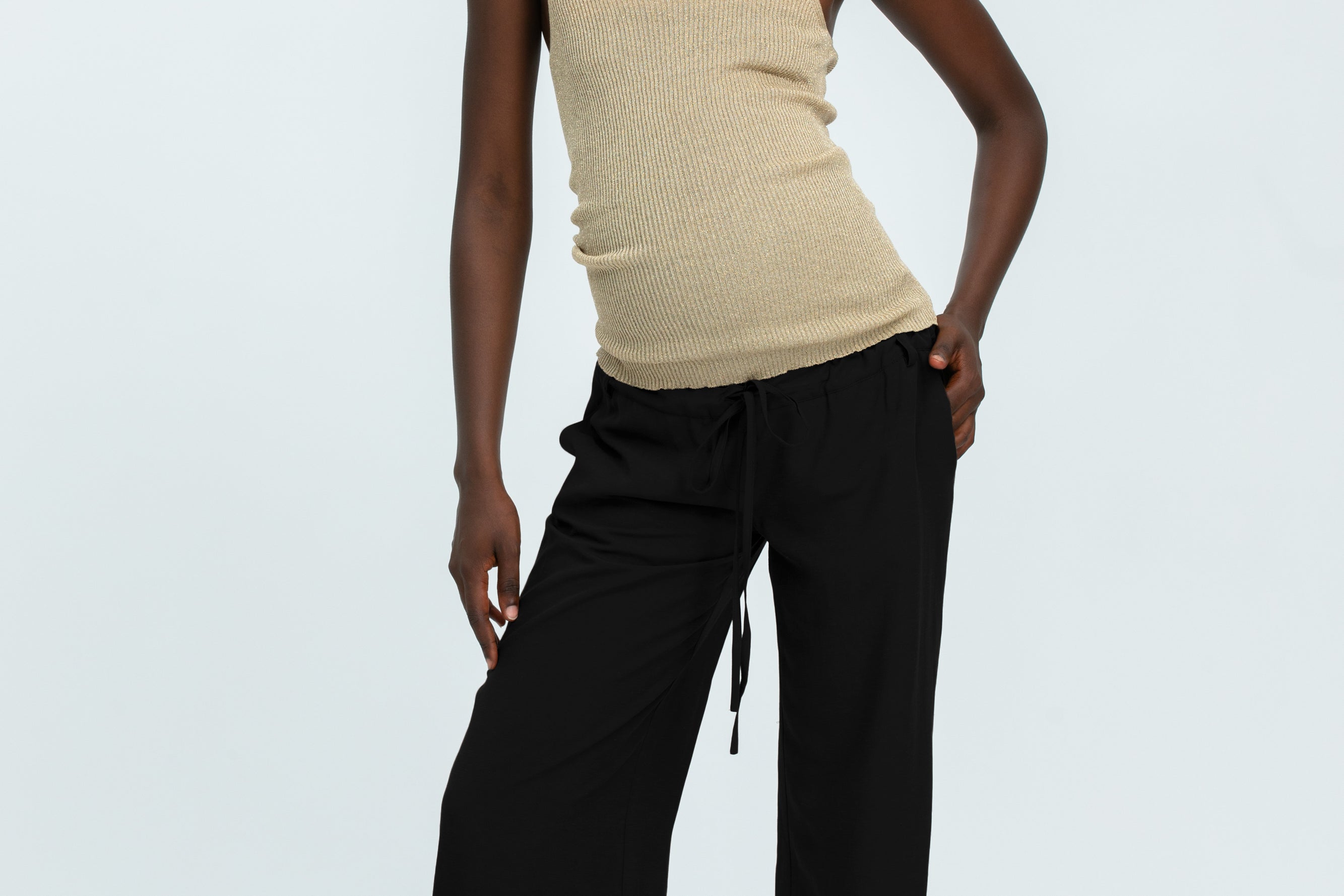 Woman wearing black linen trousers and beige vest top