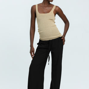 Woman wearing black linen trousers and beige vest top