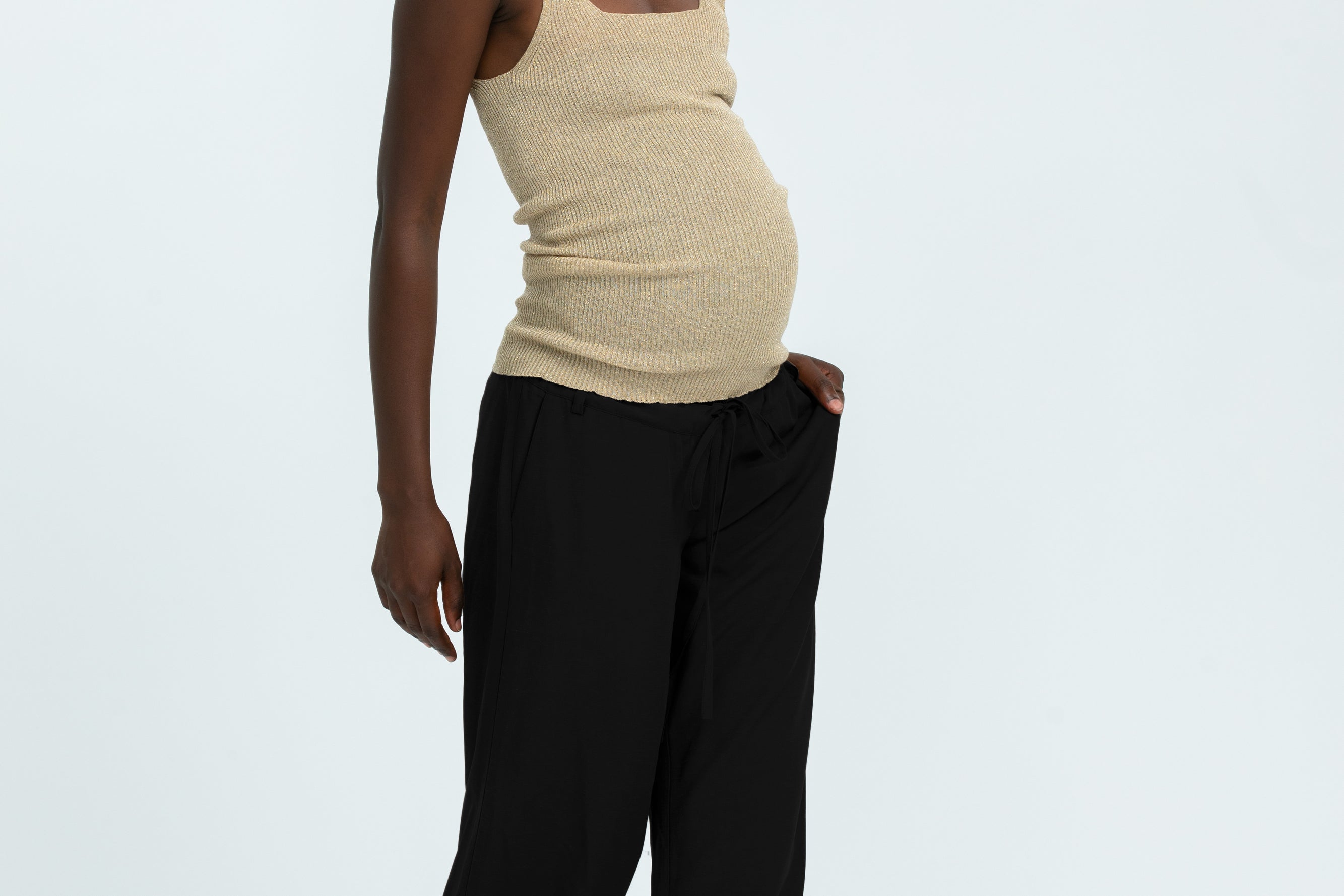 Woman wearing black linen trousers and beige vest top